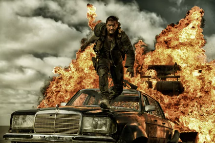 Max Rockatansky, portrayed by Tom Hardy, stands on a car against a backdrop of explosions in this intense scene from *Mad Max: Fury Road*, captured in stunning 4K Ultra HD.