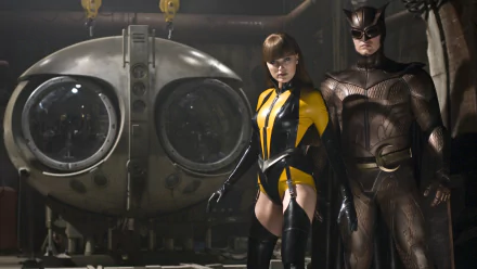 HD PC desktop wallpaper featuring two characters from the movie Watchmen standing in front of a large, vintage diving helmet in a dimly lit industrial setting.