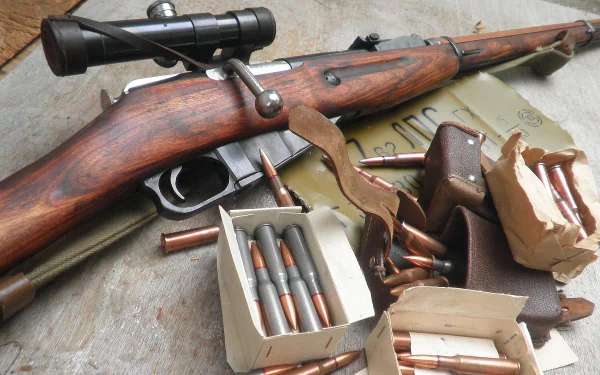 HD PC desktop wallpaper/background showing a man-made Mosin Nagant rifle with scope, boxes of ammunition and loose rounds arranged on a weathered surface.