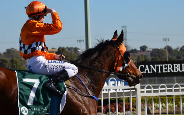 A jockey in orange attire salutes from atop a racehorse, set against the backdrop of the Sydney racecourse, capturing the excitement of horse racing.