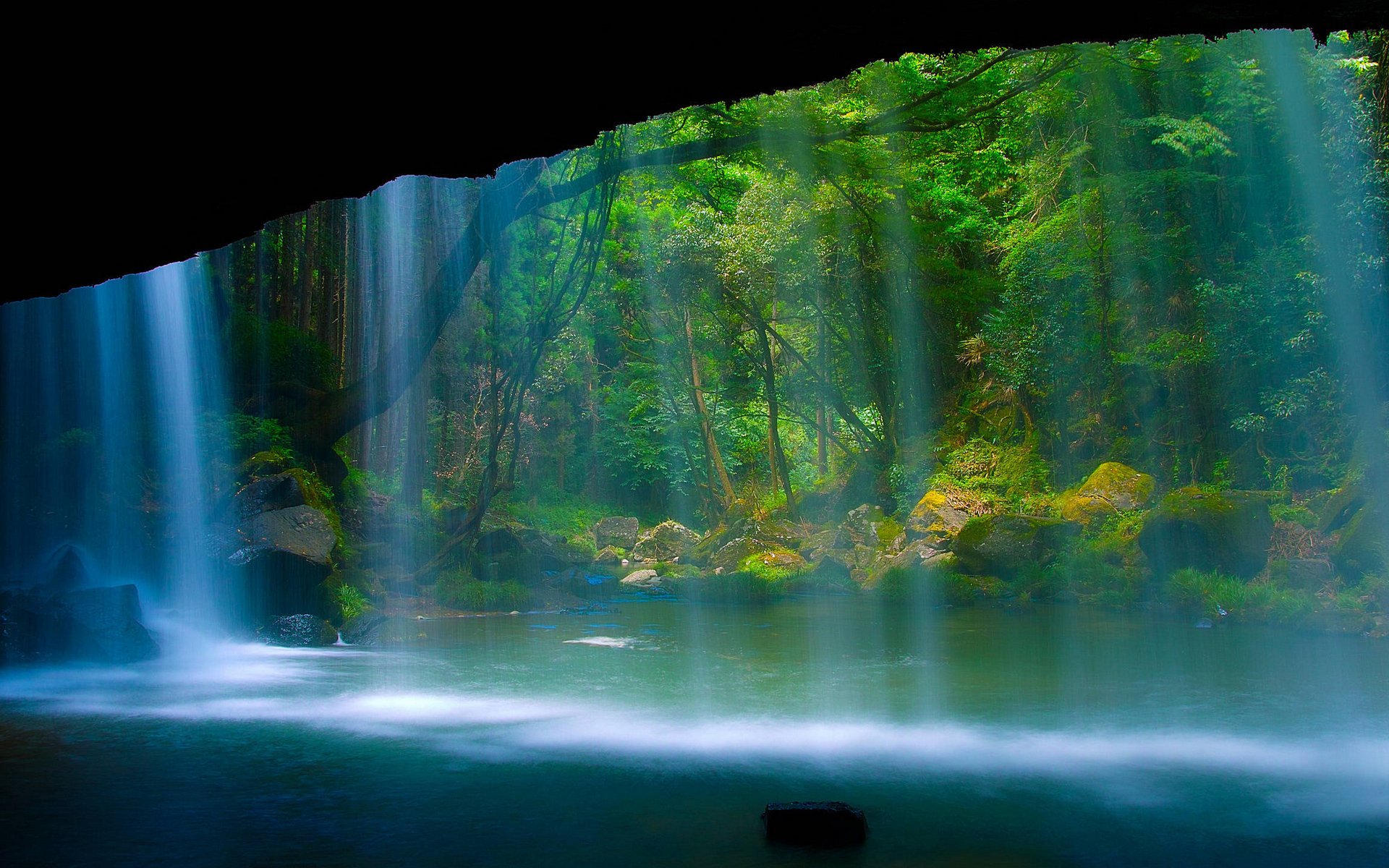 HD desktop wallpaper of a serene waterfall cascading into a misty pool surrounded by lush, vibrant greenery in a tranquil natural setting.
