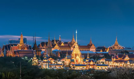 HD PC desktop wallpaper: Thailand's Grand Palace in Bangkok at night — man-made golden spires and ornate roofs glowing against a deep blue sky.