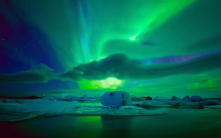 A stunning HD wallpaper featuring the aurora borealis, with vibrant green and blue hues illuminating the night sky above an icy landscape.