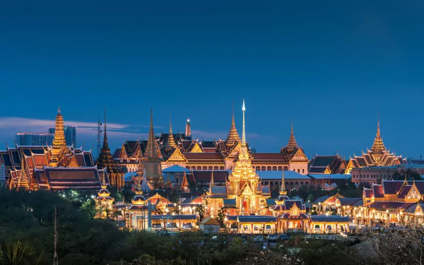 HD PC desktop wallpaper: Thailand's Grand Palace in Bangkok at night — man-made golden spires and ornate roofs glowing against a deep blue sky.