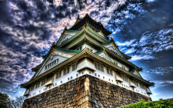 4K Ultra HD image of Osaka Castle in Japan showcasing the detailed architecture against a dramatic cloudy sky, highlighting this iconic man-made landmark.