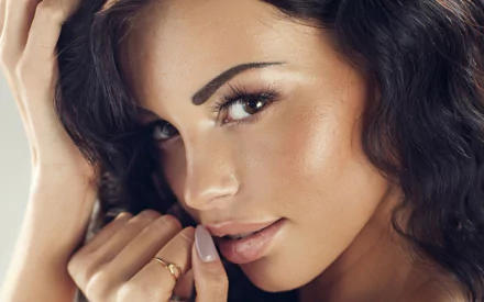 Close-up portrait of a woman's face with dark wavy hair, luminous skin and a soft smile — HD PC desktop wallpaper/background.