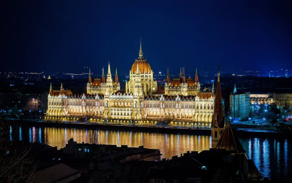 Night view of the illuminated Hungarian Parliament Building in Budapest, Hungary, reflecting on the Danube River in this HD desktop wallpaper.