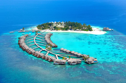 Aerial view of a tropical Maldives atoll with overwater bungalows, crystal-clear sea, and lush greenery, captured in vibrant 4K Ultra HD for a serene holiday backdrop.