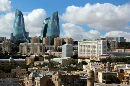 A stunning HD desktop wallpaper of Baku, Azerbaijan, showcasing the city's man-made skyline with modern skyscrapers and historic buildings under a partly cloudy sky.
