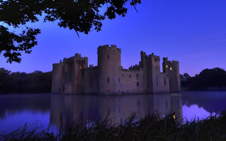 HD desktop wallpaper showcasing the man-made Bodiam Castle illuminated at dusk, reflected in the calm surrounding water.