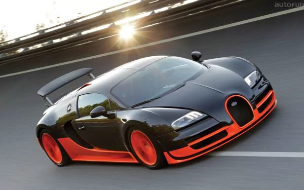 HD desktop wallpaper featuring a Bugatti Veyron, showcasing its sleek design and dynamic motion on a racetrack. The car is predominantly black with striking orange accents.