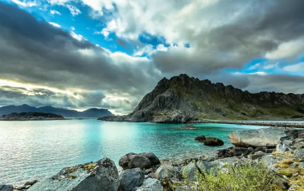 HD PC desktop wallpaper featuring a serene natural landscape with rocky ridges, calm water, and a dramatic cloudy sky.