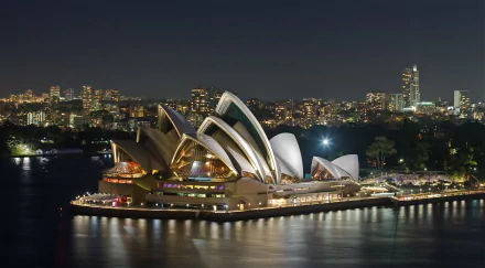 A stunning night view of the Sydney Opera House illuminated against the city skyline, showcasing the beauty of Sydney, Australia in this HD desktop wallpaper.