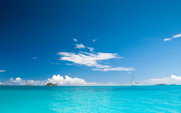 4K Ultra HD PC desktop wallpaper: turquoise sea to the horizon beneath a wide blue sky with scattered white clouds, a small island and a distant sailboat.