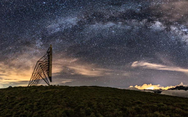 A stunning 4K Ultra HD wallpaper featuring a sci-fi inspired scene, showcasing the Milky Way galaxy above a silhouette of an antenna on a serene hillside.