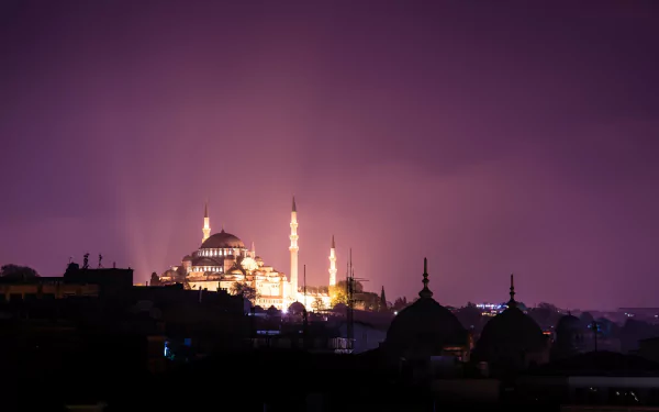 Illuminated Süleymaniye Mosque glows against a dark night sky, showcasing its stunning architecture and religious significance in Islam. A captivating HD wallpaper for any desktop.
