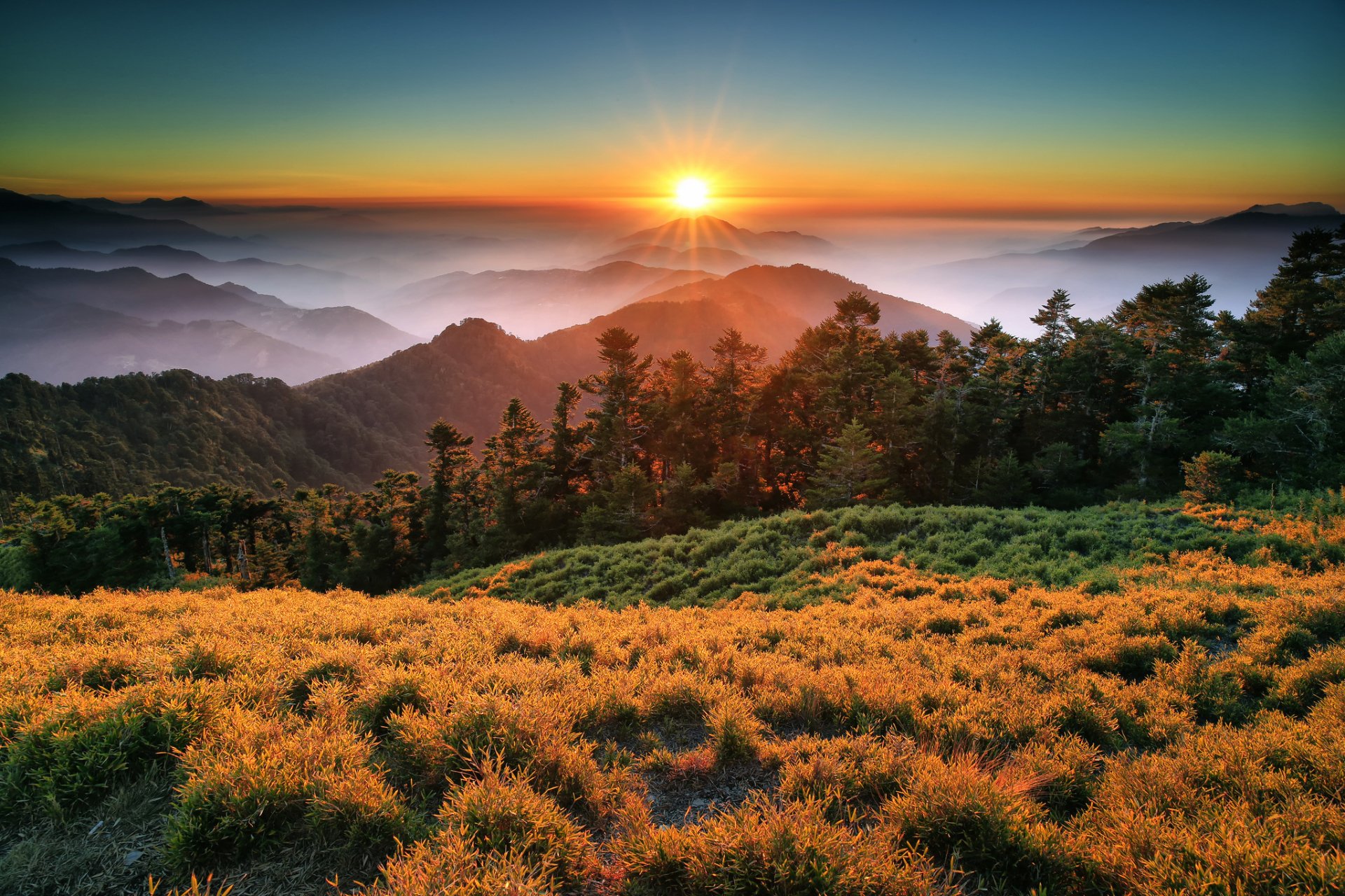 A stunning sunset illuminates the fog-covered mountains of Taroko National Park in Taiwan, with sunbeams breaking through the lush forest landscape. A captivating natural scene.