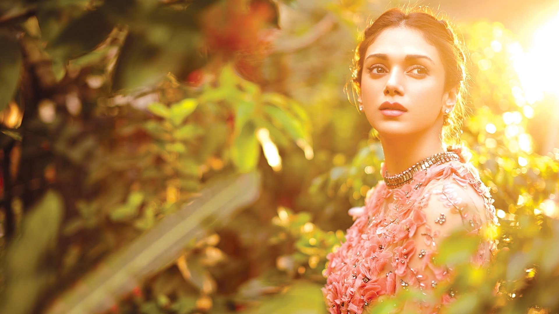 Aditi Rao Hydari bathed in warm sunshine, surrounded by lush greenery in this vibrant HD PC desktop wallpaper featuring the Indian celebrity.