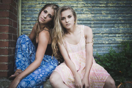 HD PC desktop wallpaper featuring two women sitting closely together against a textured metal backdrop, conveying a sense of love and connection.