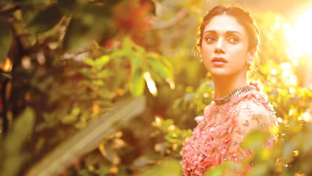 Aditi Rao Hydari bathed in warm sunshine, surrounded by lush greenery in this vibrant HD PC desktop wallpaper featuring the Indian celebrity.