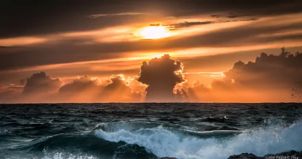 HD desktop wallpaper showcasing a dramatic sunset over ocean waves, with striking clouds illuminating the vibrant sky in this captivating nature scene.