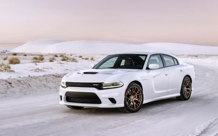 A white Dodge Charger SRT driving on a snowy road with snowy hills in the background, captured in a high-definition desktop wallpaper image.