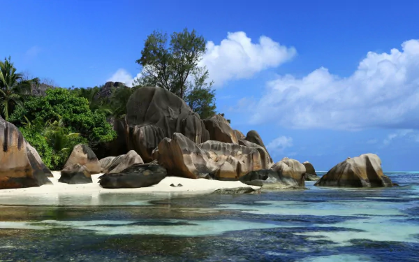 HD PC desktop wallpaper: tropical nature scene with turquoise sea, white-sand beach and granite boulders beneath a bright blue sky in the tropics.