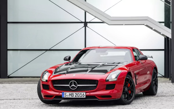 HD desktop wallpaper featuring a red Mercedes-Benz SLS AMG sports car parked in front of a modern industrial building.