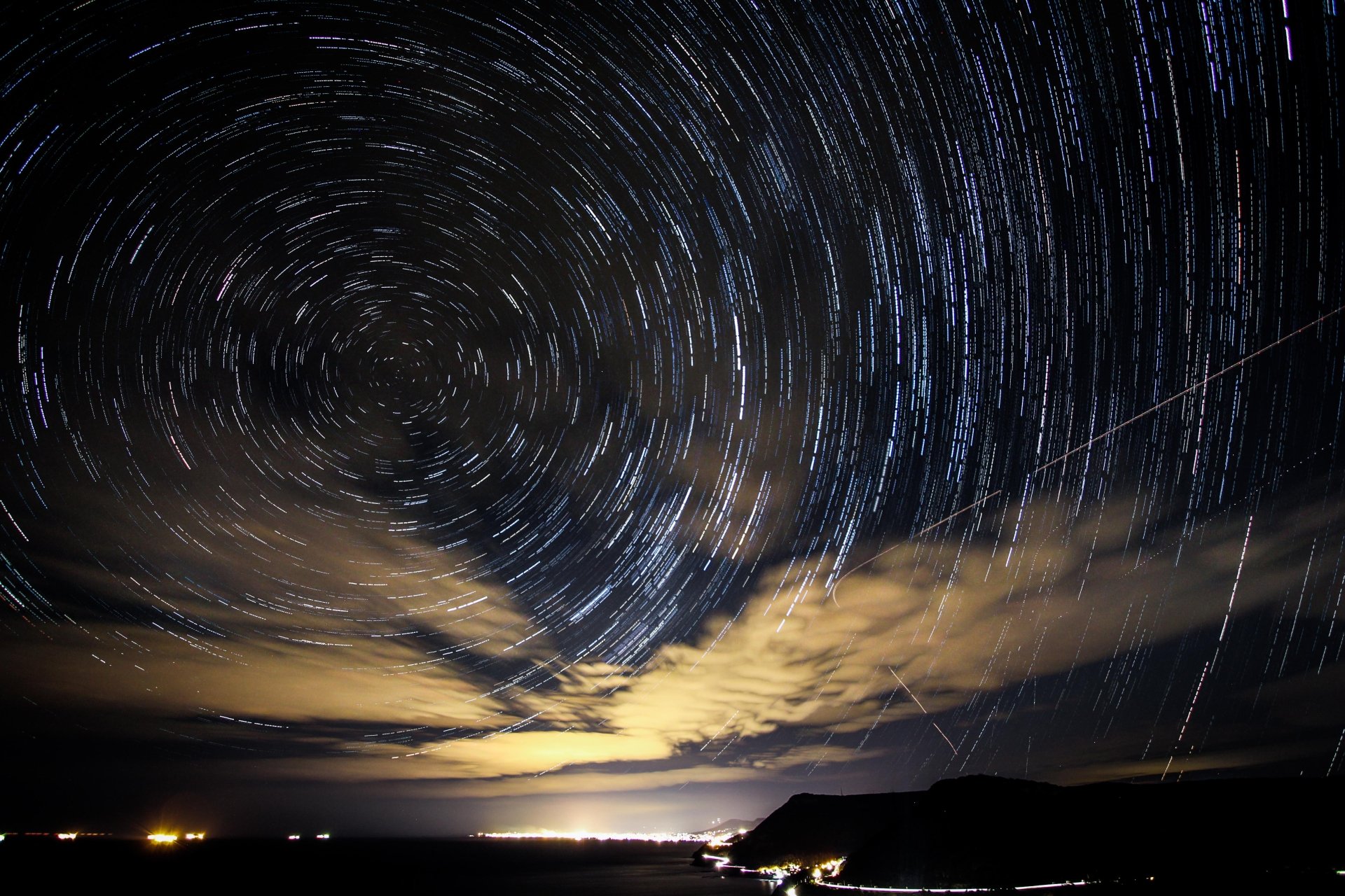 Time-lapse image of swirling star trails above a dark horizon with sci-fi ambiance, rendered in stunning 4K Ultra HD for a PC desktop wallpaper.