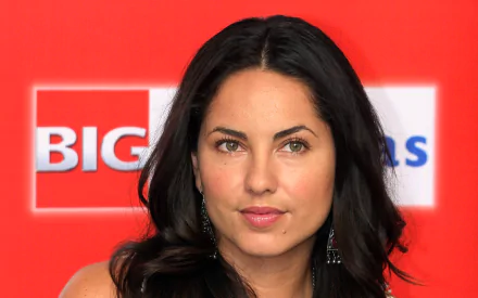 A striking HD desktop wallpaper featuring Mexican actress Barbara Mori, showcasing her captivating expression against a vibrant red background.