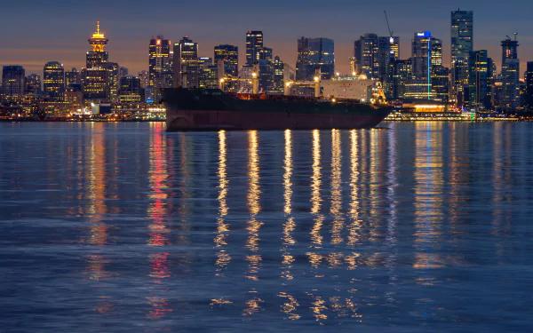 Night view of a large ship anchored in Vancouver, Canada, with city lights reflecting on the calm water in this 4K Ultra HD desktop wallpaper.