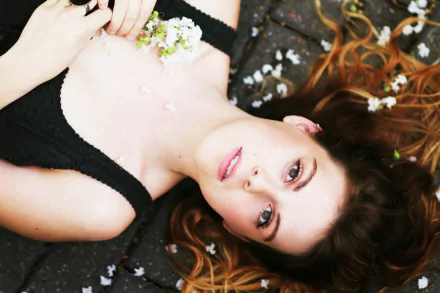 HD desktop wallpaper of a woman lying on the ground with flowers scattered around, capturing a serene and reflective mood.