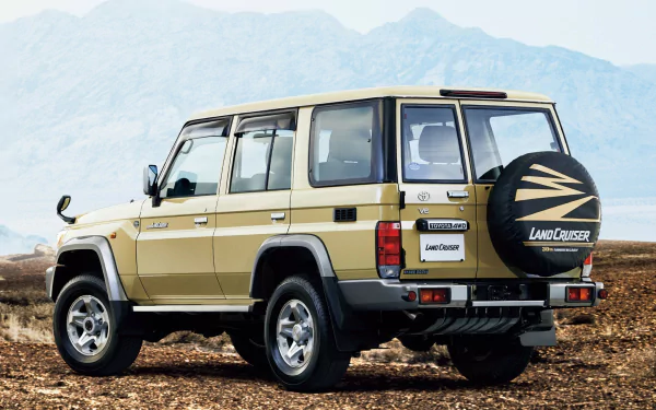 HD PC Desktop Wallpaper and Background: beige Toyota Land Cruiser parked on rocky ground with mountains in the distance, rear three-quarter view.