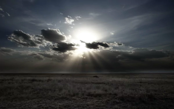 A dramatic nature scene with sunbeams breaking through dark clouds over a vast, open landscape, captured in stunning 4K Ultra HD quality for PC desktop wallpaper.
