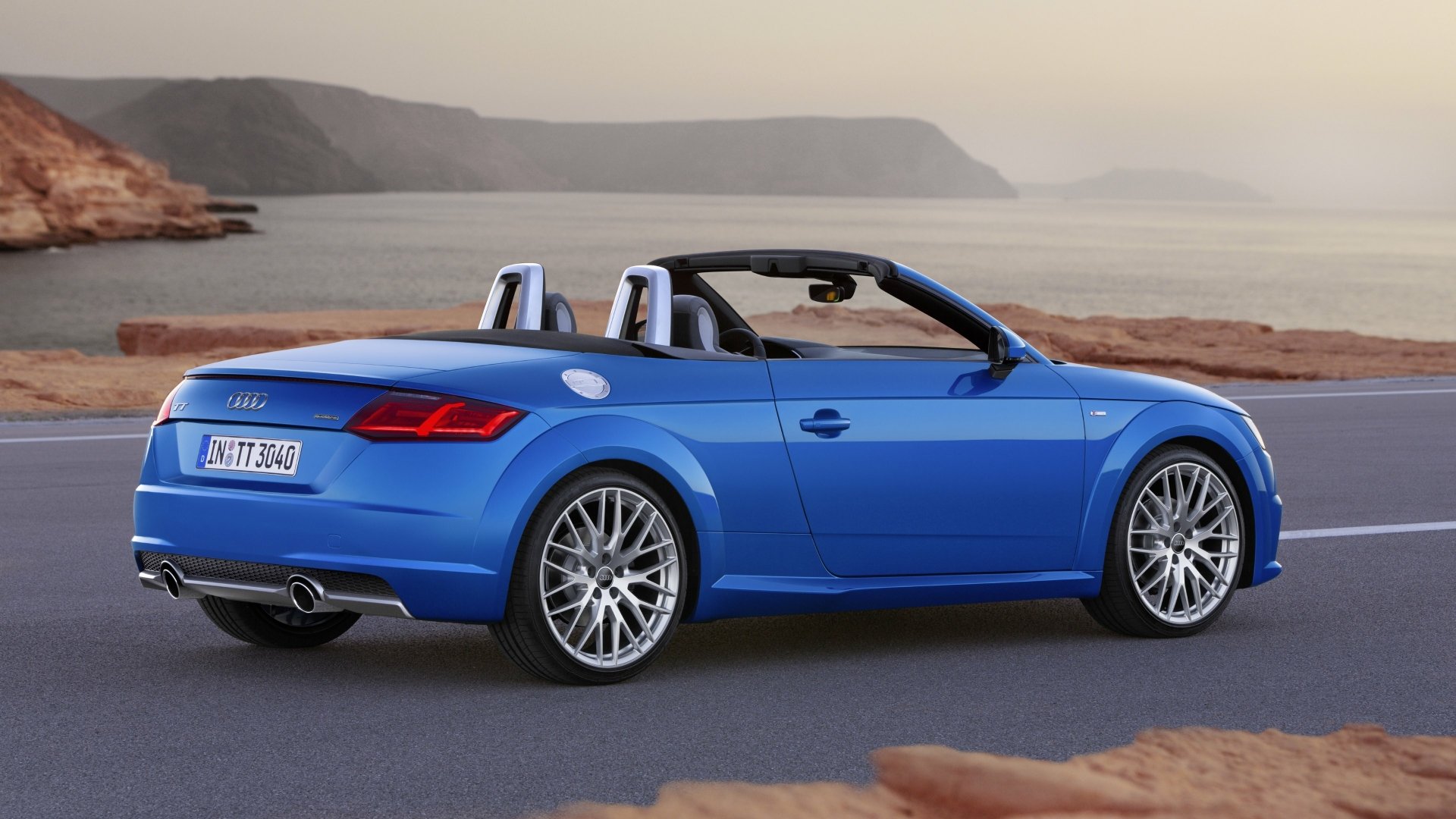 Blue Audi TT Roadster vehicle, a convertible, parked on a coastal road at sunset — 4K Ultra HD PC desktop wallpaper and background.