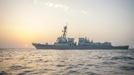 A stunning view of the USS Truxtun (DDG-103), a U.S. Navy destroyer, silhouetted against a sunset, showcasing its military prowess on the tranquil waters. 4K Ultra HD desktop wallpaper.