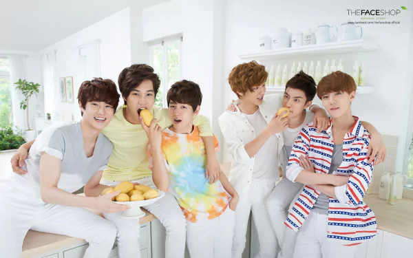 HD desktop wallpaper featuring the music group EXO. Members are seen in a bright, white kitchen setting, casually hanging out and interacting with each other.