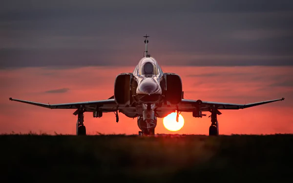 A striking HD wallpaper of a McDonnell Douglas F-4 Phantom II jet fighter, silhouetted against a vibrant sunset, showcasing its military elegance and powerful presence.