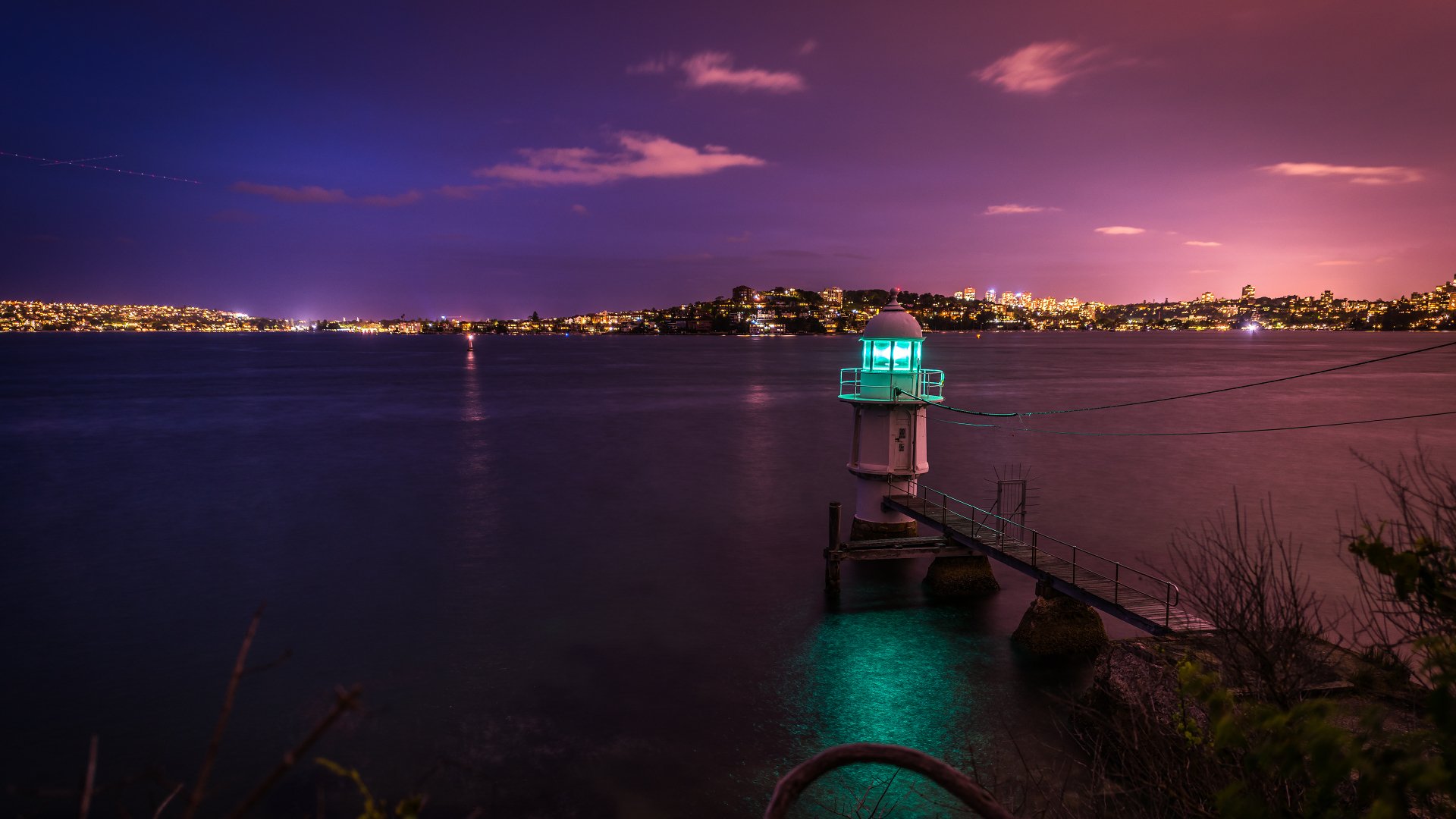 A serene seascape featuring a lighthouse illuminated against a vibrant twilight sky, capturing the beauty of man-made structures amidst nature's tranquility in 4K Ultra HD.