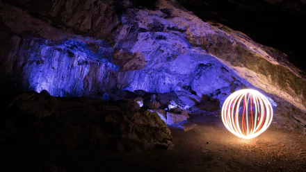 Night photography of a cave bathed in blue-purple light with a glowing orb of fireworks-style light painting; 4K Ultra HD PC desktop wallpaper and background.