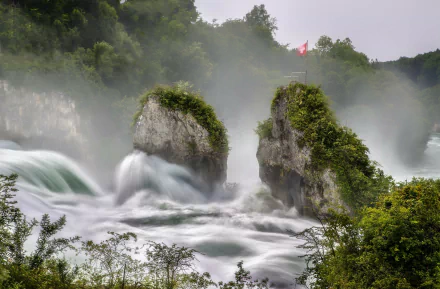 Powerful torrent of water cascades around moss-covered rocks with the Swiss flag above, set in lush greenery, capturing the raw energy and beauty of nature in HD.
