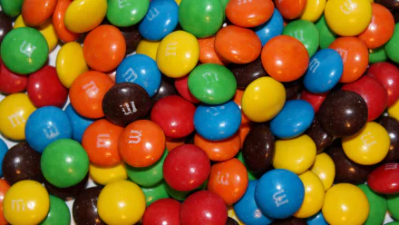 4K Ultra HD PC desktop wallpaper showing a close-up of man-made M&M's: glossy red, blue, yellow, green, orange and brown candy-coated chocolates piled together.
