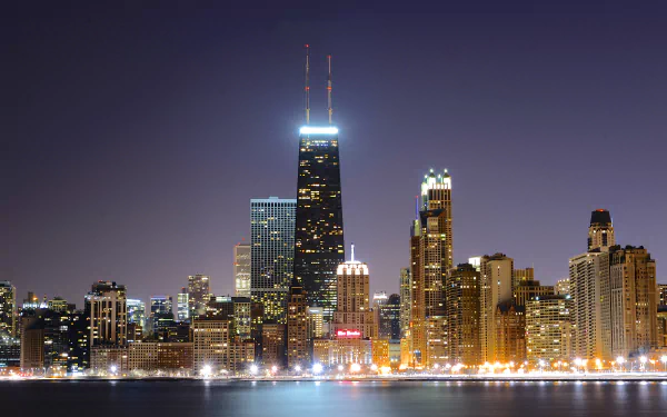 A stunning night view of Chicago’s skyline, showcasing illuminated skyscrapers reflecting on the water. This 4K Ultra HD desktop wallpaper captures the city's vibrant spirit.