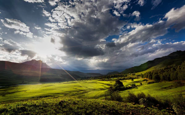 Sunlight breaks through dramatic clouds over a lush green landscape in South Africa, creating a vibrant natural scene captured in HD for a desktop wallpaper background.