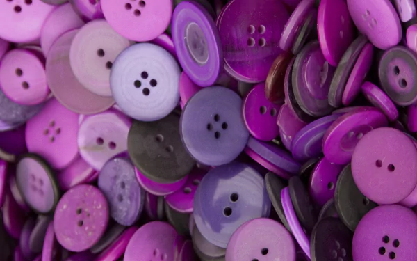 Close-up of piled purple and pink man-made buttons in varying shades and sizes — 2K Quad HD PC desktop wallpaper/background.