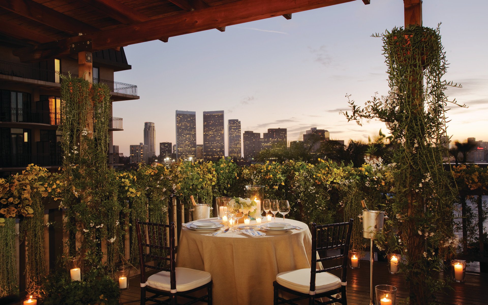 HD PC desktop wallpaper and background: rooftop candlelit dining on a verdant terrace, overlooking the Los Angeles skyline at dusk — a man-made urban scene.