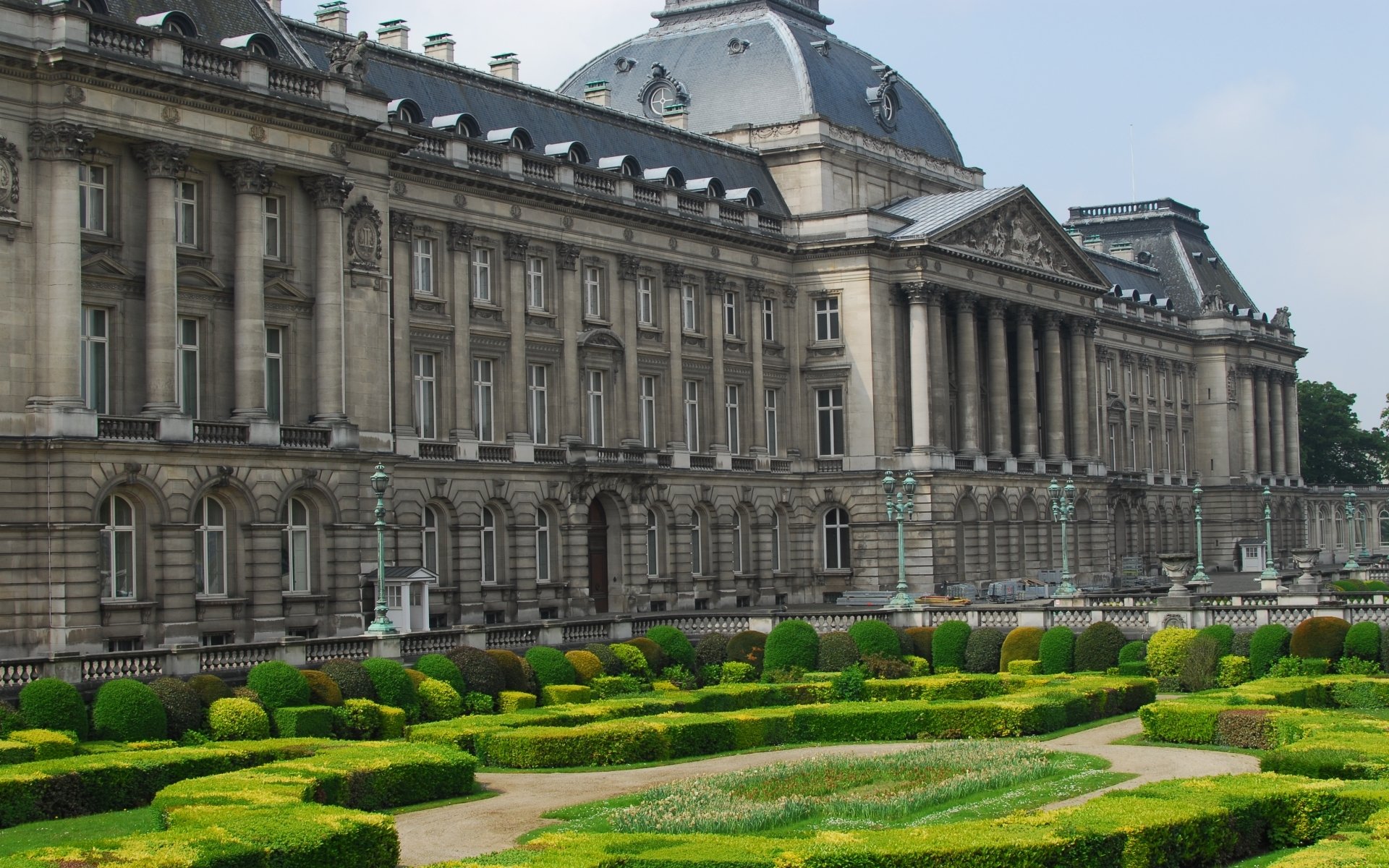HD desktop wallpaper featuring the Royal Palace of Brussels, showcasing its grand architecture and manicured gardens under a clear sky.