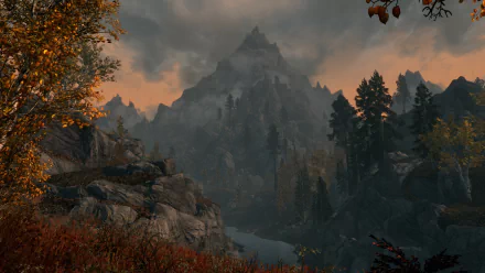 A scenic HD PC desktop wallpaper from The Elder Scrolls V: Skyrim featuring a forested landscape with a river flowing through and a towering mountain under a cloudy sky.