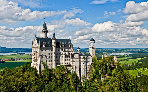 HD wallpaper of Neuschwanstein Castle in Germany, showcasing the majestic castle amid lush greenery and a vibrant sky.