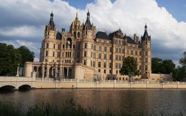 Schwerin Palace, Germany — ornate man-made palace reflected in a calm lake beneath blue skies; 2K Quad HD PC desktop wallpaper and background.